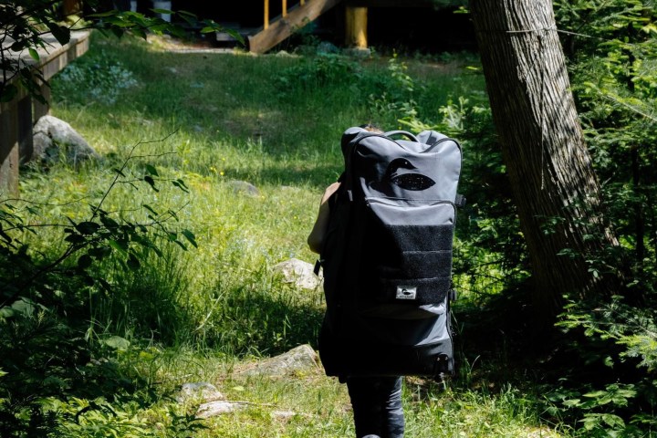 woman carrying an inflatable paddleboard in a convenient backpack to the cabin