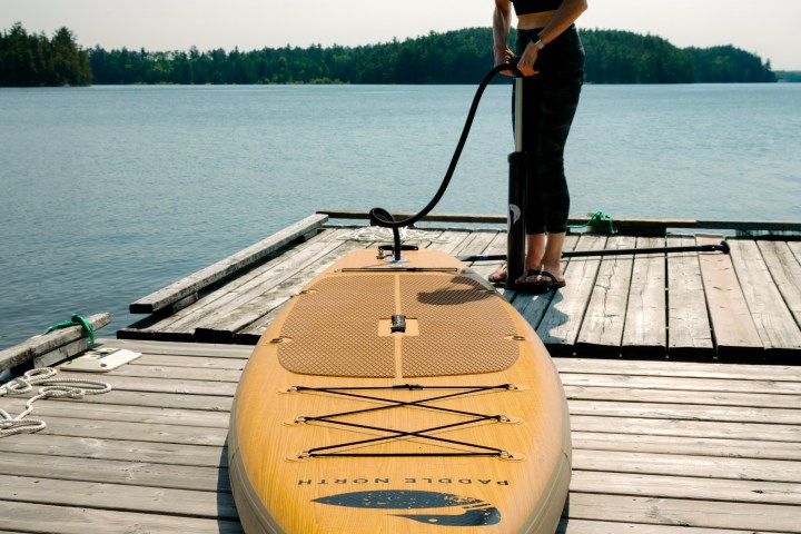 woman inflating a stand-up paddleboard on a dock
