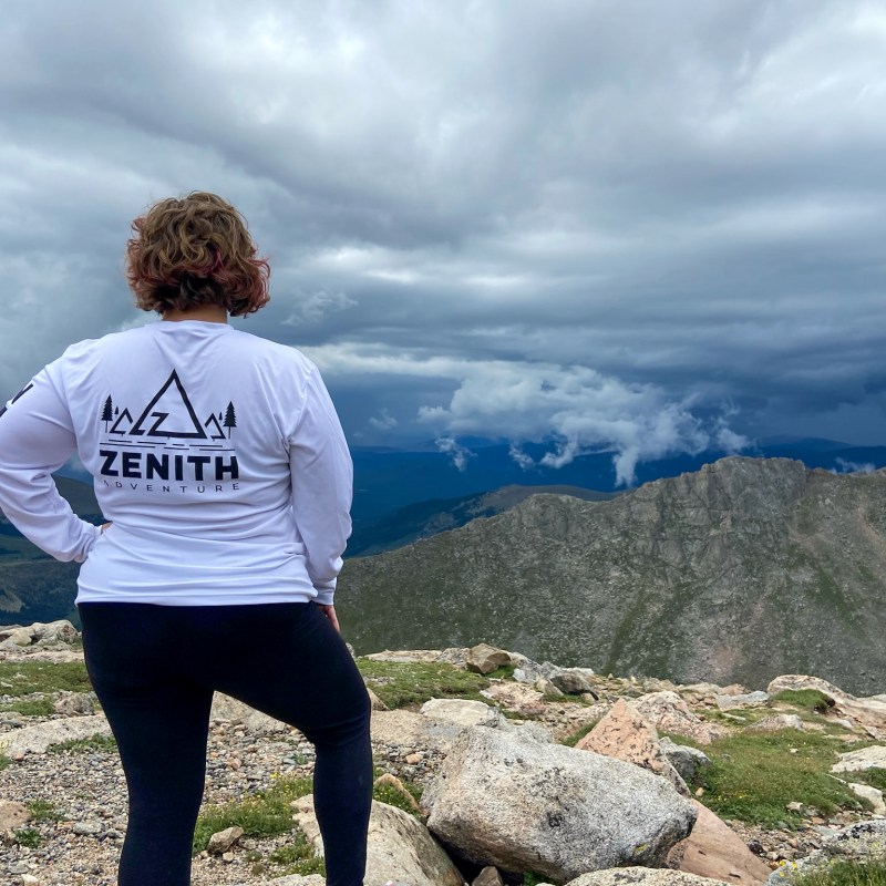 a woman standing on top of a mountain in Zenith Adventure shirt