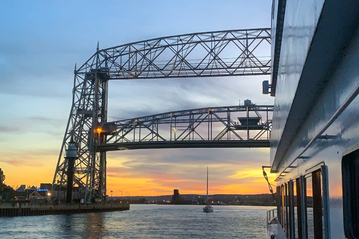 View of bridge and sunset from a ship's deck, with a calm waterway.