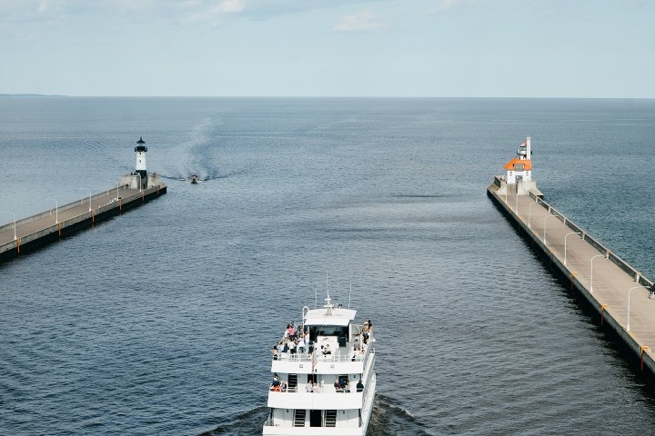 A boat sailing between two piers under a cloudy sky.
